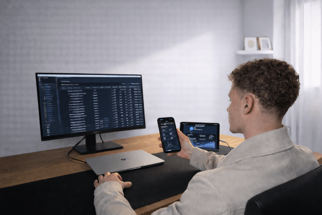 Social Media Manager analysiert Kampagnen und Performance auf Smartphone und Desktop Monitor im Büro